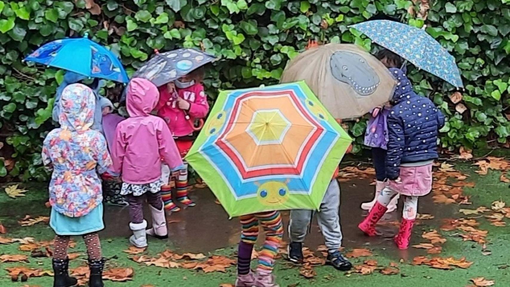 Children holding umbrellas playing in a puddle